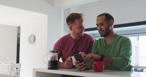 Interracial Gay Couple Enjoying Breakfast with Smartphone Interaction