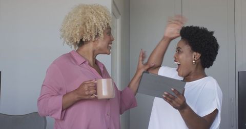 Joyful friends laughing during coffee break with tablet