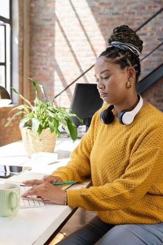 Focused African American Woman Writing Notes in Modern Office
