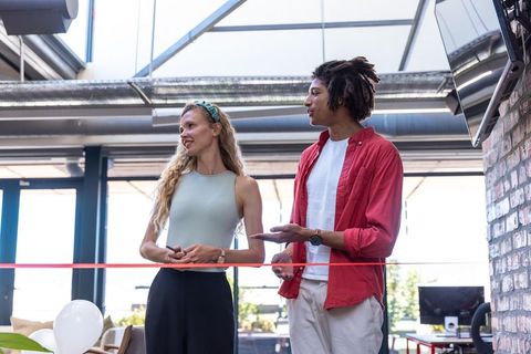 Diverse coworkers participating in office ribbon-cutting event