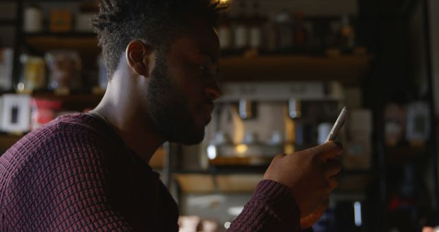 Young Man Using Smartphone in Dimmly Lit Cafe - Download Free Stock Images Pikwizard.com