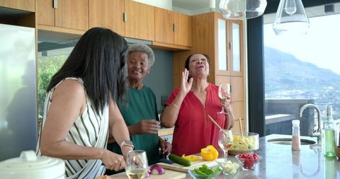 Multigenerational african american women cooking and laughing at kitchen island