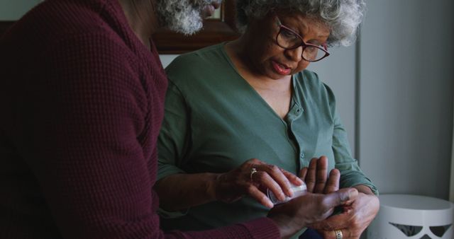 Senior biracial woman examines medication at home, with copy space. Gentle guidance from a partner ensures proper healthcare management.