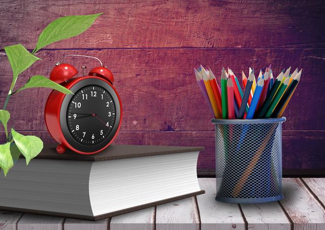 Alarm clock on book with colorful pencils against wooden background