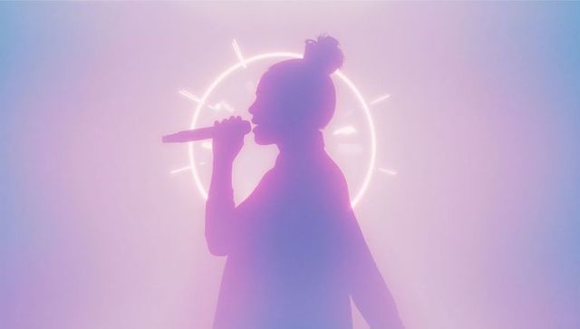 Female singer performing on vibrant stage with neon lights
