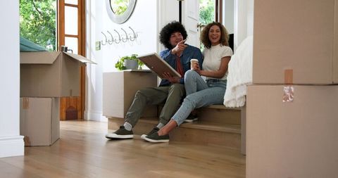 Smiling couple enjoying coffee in new home surrounded by moving boxes