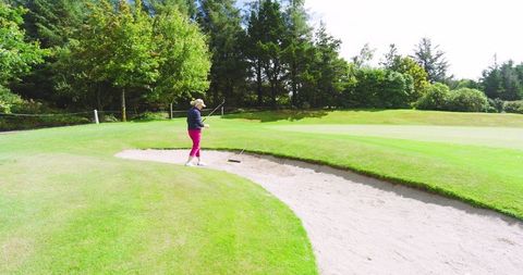 Senior golfer at sand trap on green country course