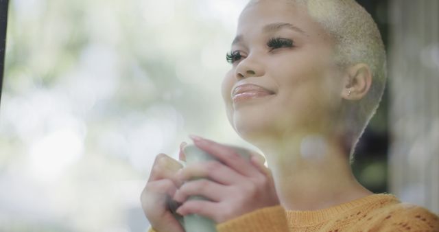 Young woman enjoying a hot beverage in a cozy sweater by the window - Download Free Stock Images Pikwizard.com