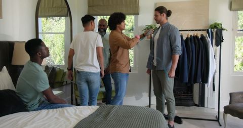 Groom fitting suit with friends wedding preparation ritual