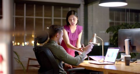Focused colleagues collaborating on tech project late at night
