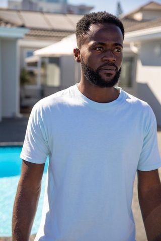 Thoughtful Man Relaxing by Pool in Modern Tropical Backyard
