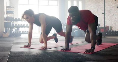 Diverse Athletes Performing Plank Knee Tucks at Fitness Studio