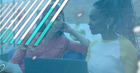 Women collaborating over analytics dashboard on laptops in modern coworking lounge