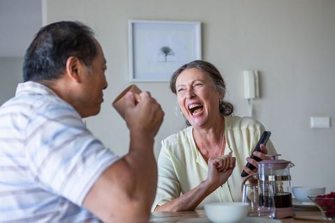 Smiling Senior Couple Enjoying Coffee and Technology at Home
