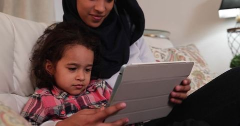 Mother and daughter bonding over tablet technology at home