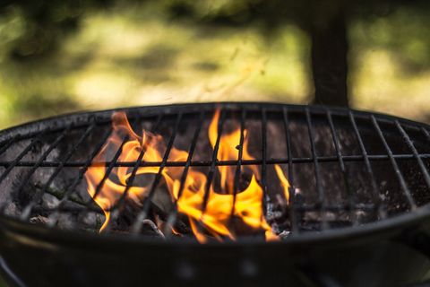 Close-up flaming charcoal grill showing bright flames for outdoor barbecue cooking