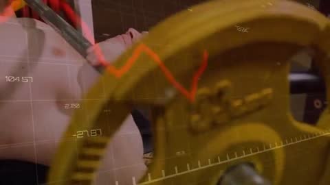 Man bench-pressing heavy barbell with yellow plate while performance analytics tracking