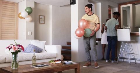Friends preparing birthday celebration at home, holding party decorations