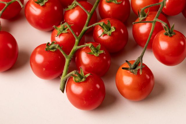 Close-up of fresh organic red tomatoes on a table. Ideal for use in food blogs, healthy eating articles, organic produce promotions, and cooking websites. Perfect for illustrating concepts related to nutrition, vegan and vegetarian diets, and farm-to-table produce.