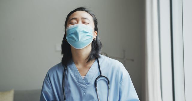 Portrait of happy asian female nurse wearing face mask holding tablet in hospital, smiling to camera. medicine, health and healthcare services during coronavirus covid 19 pandemic.