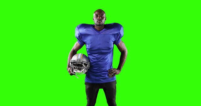 Football player standing confidently with a helmet on green screen background. Useful for sports team promotions, athlete spotlight features, or virtual background inserts.