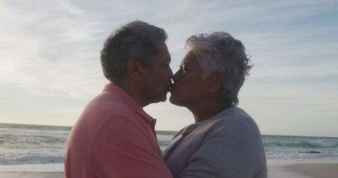Senior Couple Sharing Romantic Sunset Kiss on Beach
