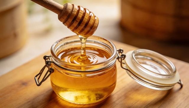 Rustic Honey Jar with Wooden Dipper Dripping Golden Honey Over Wooden Board Close-up