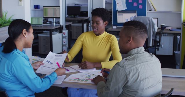 Group of African American colleagues discussing business documents and data in an office environment. Ideal for depicting professional teamwork, business meetings, data analysis, and collaborative work settings.