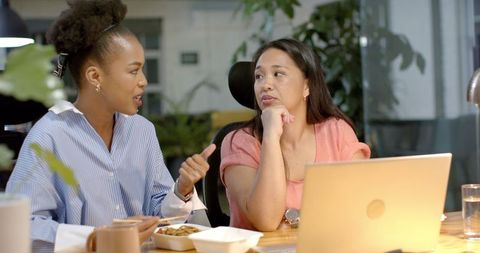 Businesswomen collaborating on laptop during evening meal