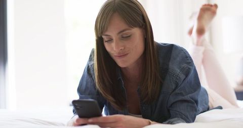Relaxed Middle-Aged Woman Enjoying Smartphone Time in Bright Bedroom - Download Free Stock Images Pikwizard.com