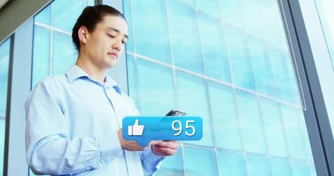 Businessman checking smartphone receiving 95 likes notification beside modern office window