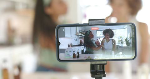 Filming skincare tutorial in bright home kitchen with smartphone tripod and amber bottles