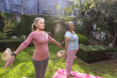 Senior women practicing yoga in peaceful garden setting