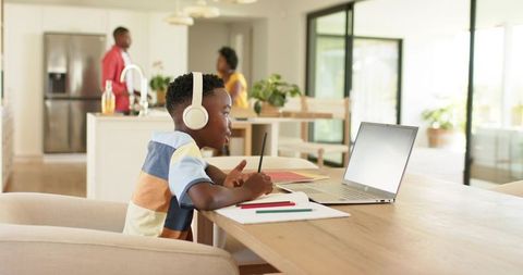 African American Boy Studying on Laptop at Home Kitchen Table Wearing Headphones
