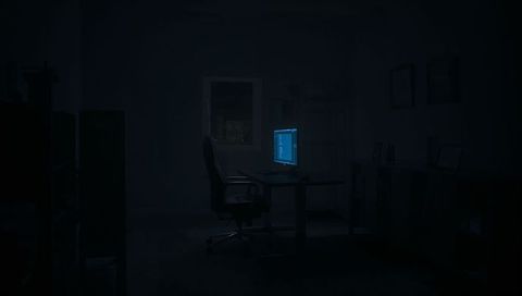 Glowing blue monitor casting code light on ergonomic chair in nighttime home office