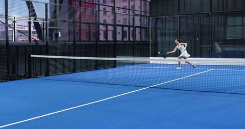 Female tennis player in action on modern indoor blue court