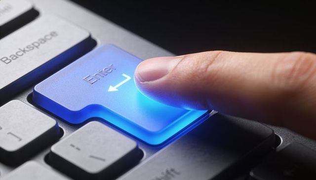 Pressing glowing blue enter key closeup finger press on backlit keyboard for tech