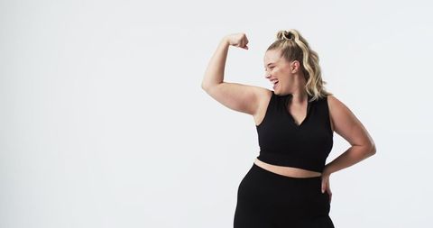 Confident Plus Size Woman Flexing Arm in Black Workout Clothes