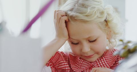 Young Child in Red Outfit Concentrating While Seated at Desk