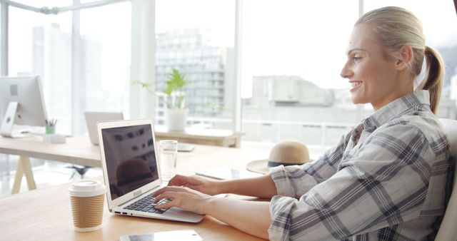 Cheerful businesswoman working on laptop in modern office - Download Free Stock Images Pikwizard.com