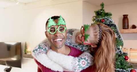 Joyful Couple Celebrating Christmas with Tree Glasses and Laughter
