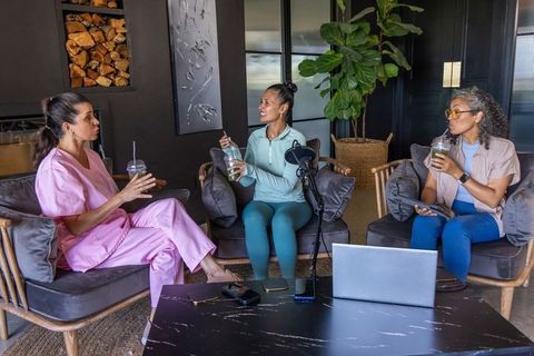 Diverse female colleagues recording podcast and discussing wellness in cozy modern lounge