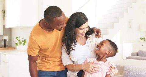 Smiling parents sharing warm moment on sofa in bright open-plan kitchen, family bonding