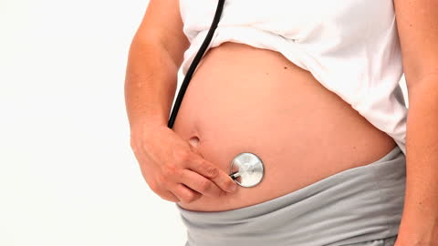 Pregnant Woman Using Stethoscope on Belly for Baby Listening