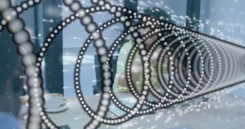 Concentric dot glass partition framing colleagues chatting over coffee in office lounge