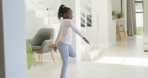 African girl practicing balance pose in bright minimalist living room for home fitness