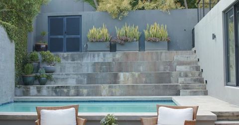 Minimalist modern pool terrace with wicker lounge chairs and potted succulents