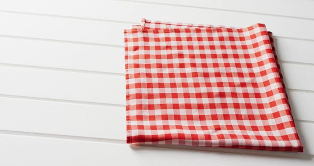 Close up of folded red and white checkered blanket on white background with copy space. Picnic day, food and nature concept.