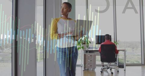 Holding laptop and analyzing data with colleague in minimalist glass office