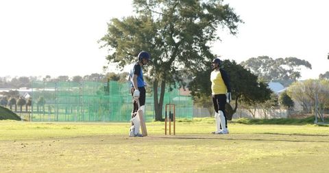 Cricket Players in Action on Field Discussing Strategy